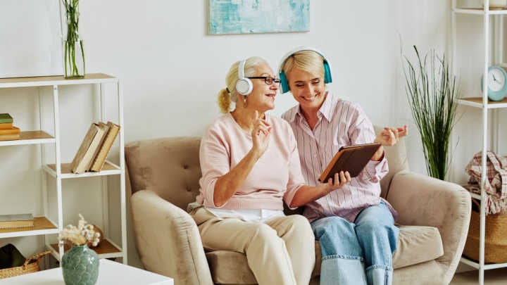 Zwei Frauen sitzen auf einem Sofa und schauen auf ein Laptop.